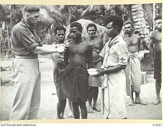 1943-10-08. NEW GUINEA. AT KAIAPIT. SGT. H. COX OF BURWOOD, N.S.W. GIVES MEDICAL ATTENTION TO NATIVES. A WEEK PREVIOUSLY THESE NATIVES HAD BEEN CONTROLLED BY THE JAPANESE. (NEGATIVE BY G. SHORT)