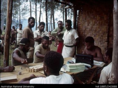 Men seated counting coins