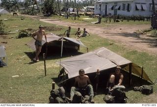 A camp, 8 Troop's home for almost two weeks at the village of Pangi, Lifuka Is.  Sapper Geoffrey Maxwell standing, seated left to right Lance Corporal's Shane Harrop and Bob West.  In the ..