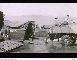 LAE, NEW GUINEA. 1943-10-17. TROOPS OF THE 29/46TH AUSTRALIAN INFANTRY BATTALION UNLOADING PROVISIONS FROM THE TRUCK INTO THE BARGE "THE DUCHESS" ON THE BEACH