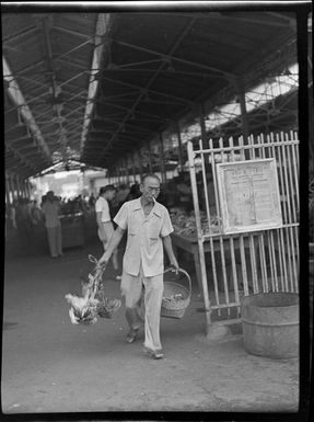 Market scene with man leaving with basket and chickens, Papeete, Tahiti