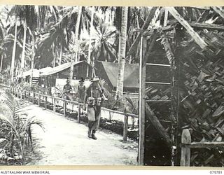 SIAR-NAGADA, NEW GUINEA. 1944-09-08. THE ADMINISTRATION AREA, WITH A SENTRY ON THE BEAT, IN THE CAMP AREA OF THE 61ST INFANTRY BATTALION "THE QUEENSLAND CAMERON HIGHLANDERS". SEEN ARE:- QX48864 ..