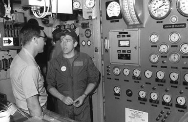 Secretary of the Navy John F. Lehman Jr., right, and CDR Nicholas Stasko tour a boiler room during Lehman's visit aboard the aircraft carrier USS KITTY HAWK (CV-63)