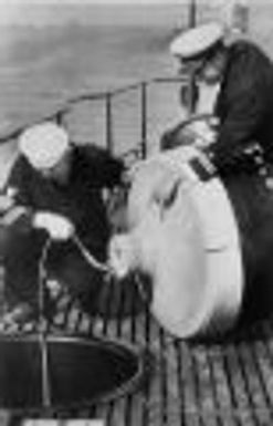 Sailors aboard the U.S.S. Permit inspect telephone marker