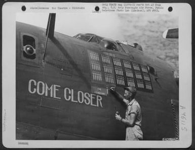 Cew Chief Of The Consolidated B-24 Liberator 'Come Closer' Paints The 91St Bomb On Nose Of The Plane Ti Indicate The Missions That The Plane Has Flown. The Three Jap Flags Painted On The Plane Indicates That Its Crew Has Shot Down 3 Jap 'Zeros'. Saipan, (U.S. Air Force Number 64389AC)