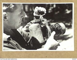 NAMBARIWA, NEW GUINEA. 1944-01-21. AN AUSTRALIAN ARMY OFFICER EXAMINING AN ACETYLENE SIGNAL LAMP WHICH WAS AMONG A LARGE QUANTITY OF STORES WHICH THE JAPANESE ABANDONED DURING THEIR RETREAT FROM ..