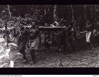 FARIA VALLEY, NEW GUINEA. 1943-10-16. SX17161 PRIVATE L. G. AGARS OF THE 2/27TH AUSTRALIAN INFANTRY BATTALION BEING CARRIED BY FOUR NATIVE STRETCHER BEARERS FROM GUY'S POST TO THE MAIN DRESSING ..