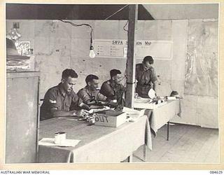 GREEN ISLAND, BOUGAINVILLE AREA, SOLOMON ISLANDS. 1944-12-19. MEMBERS OF THE INTELLIGENCE SECTION, HQ 23 INFANTRY BRIGADE AT WORK IN THE BATTLE ROOM AT BDE HQ. IDENTIFIED PERSONNEL ARE:- CORPORAL M ..