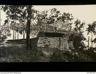 Port Moresby, New Guinea. 1942. Exterior view of the operations room of the 67th Anti-Aircraft Searchlight Battery. The walls of the operations room are made of sandbags, and the roof is covered ..