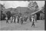 Returned laborers (in western clothing), their kin inspect new-style house built by the returnees