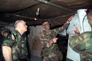 Army CHIEF of STAFF General (GEN) Carl E. Vuono, left, receives a briefing from an officer with the 25th Infantry Division (Light), in the tactical operations center during a visit to the training area
