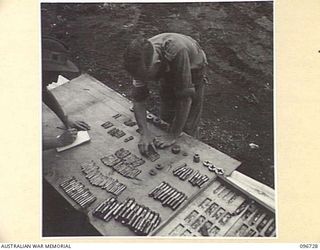 MOEM, WEWAK AREA, NEW GUINEA, 1945-09-17. CORPORAL W.L. READ (1) AND SERGEANT N. CHAMPION (2) MEMBERS OF 2/4 ARMOURED REGIMENT DETACHMENT WITH 4 INFANTRY TROOPS WORKSHOP, CHECKING DIES OUTSIDE THE ..