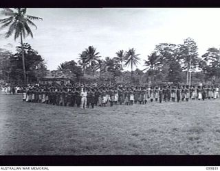 LAE, NEW GUINEA, 1946-02-14. MEMBERS OF THE ROYAL PAPUAN CONSTABULARY AND CIVILIAN PERSONNEL CROWDED THE PARADE GROUND DURING AN ADDRESS BY MAJOR GENERAL B.M. MORRIS, GENERAL OFFICER COMMANDING ..