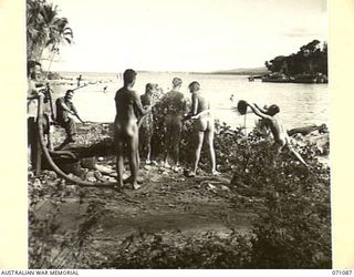 NEW GUINEA. 1944-03-10. VX10828 CAPTAIN J. SMITH (1), OFFICER COMMANDING THE 5TH DIVISION RECEPTION CAMP, WITH OFFICERS AND MEN OF THE CAMP WHO ARE HOSING EACH OTHER DOWN AFTER A BATHE IN THE BAY. ..