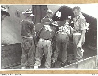 WARD'S DROME, NEW GUINEA. 1943-11-16. TROOPS OF THE 2/5TH AUSTRALIAN FIELD REGIMENT, 7TH AUSTRALIAN DIVISION, CARRYING THE SHIELD OF A 25-POUNDER GUN INTO A DOUGLAS TRANSPORT AIRCRAFT DURING AN ..