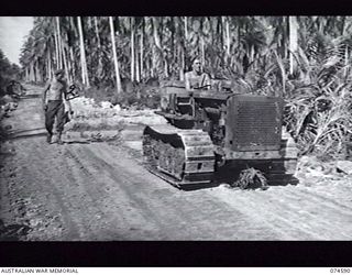 NAGADA, NEW GUINEA. 9 JULY 1944. TROOPS OF THE 8TH FIELD COMPANY, USING A TRACTOR TO DRAG A COCONUT LOG GRADER ALONG A REBUILT SECTION OF THE SIAR ROAD