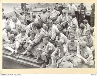 FAURO ISLAND, BOUGAINVILLE AREA. 1945-10-01. JAPANESE PATIENTS WEARING WHITE COATS SITTING ON THEIR GEAR ON AN AUSTRALIAN LANDING CRAFT WAITING THE ORDER TO UNLOAD. ALL JAPANESE MEDICAL CASES FROM ..