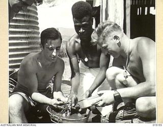 1943-06-29. NEW GUINEA. WAU-MUBO AREA. IN AN OFF MOMENT PTE. R. DAVIES, OF VIC., L/C ALLEN, OF VIC., AND PTE. JOHN LUCAS OF VIC., WITH FUZZY WUZZY MARRAMON EXAMINE THEIR IMPROVISED WASHING PANS AS ..