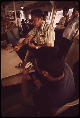 "SEA TRANSIT" FERRY HAS BEEN OPERATING FOR ONE YEAR BETWEEN DOWNTOWN HONOLULU AND PEARL HARBOR - AN ALTERNATIVE TO FREEWAY CONGESTION. IT ALSO CARRIES MILITARY-RELATED EMPLOYEES ACROSS PEARL HARBOR TO THE PARKING LOT - SAVING THEM A 45-MINUTE DRIVE. A GAME OF CARDS EN ROUTE