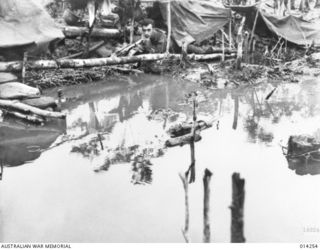 1943-01-27. PAPUA. SANANANDA AREA. HOME WAS NEVER LIKE THIS. AN AMERICAN IN THE EARLY MORNING SURVEYS WHAT HAD BEEN A DRY AREA WHEN HE SELECTED IT THE PREVIOUS NIGHT. INCHES OF RAIN FELL IN THE ..