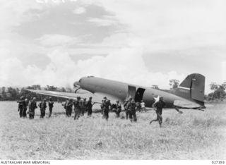 WANIGELA, NEW GUINEA. 1942-10. MEMBERS OF THE 3RD BATTALION, 128TH REGIMENT, 32ND U.S. DIVISION ALIGHTING FROM A 5TH US ARMY AIR FORCE (USAAF) C-47 TRANSPORT PLANE ON A ROUGH RUN WAY ON THE SHORES ..