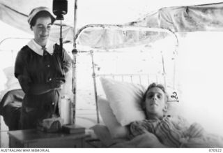 EGGY'S CORNER, PORT MORESBY AREA, PAPUA, NEW GUINEA. 1944-02-20. VFX112019 SISTER J.K. GREET, AUSTRALIAN ARMY NURSING SERVICE, (1); ADJUSTING THE FLOW OF BLOOD WHILE GIVING A TRANSFUSION TO TX5273 ..