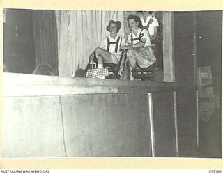 LAE, NEW GUINEA. 1944-08-11. TWO MEMBERS OF THE CAST SITTING SIDE STAGE DURING THE INN SCENE OF A PLAY STAGED BY THE WHITE HORSE INN CONCERT PARTY FOR PATIENTS OF THE 113TH CONVALESCENT DEPOT. THE ..