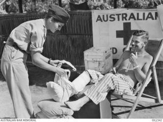 AITAPE, NORTH EAST NEW GUINEA. 1945-03-30. 501158 SISTER JOYCE PATTERSON OF BEXLEY, NSW, A RAAF FLYING NURSE, ATTENDS TO A BANDAGE ON HIS RIGHT FOOT FOR MAJOR J. L. SCOTT, OF ELSTERNWICK, VIC, ..
