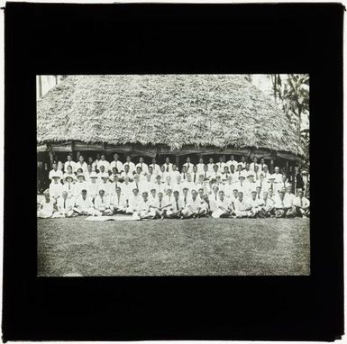 Large group of men and women outside fale (house), Samoa