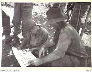 KIARIVU, NEW GUINEA, 1945-08-14. WARRANT OFFICER 2 T. HEALEY, THE AUSTRALIAN NEW GUINEA ADMINISTRATIVE UNIT REPRESENTATIVE, QUESTIONS A JAPANESE PRISONER IN THE 2/7 INFANTRY BATTALION AREA. HE ..