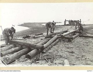 WANIGELA, NEW GUINEA. 1942-10. SAPPERS FROM 2/4TH AND 2/14TH FIELD COMPANIES, AUSTRALIAN ENGINEERS, CUTTING PILES FOR USE IN THE CONSTRUCTION OF A NEW WHARF THEY ARE BUILDING AT WANIGELA MISSION IN ..