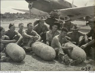 KIRIWINA, TROBRIAND ISLANDS, PAPUA. 1943-12-26. AN INFORMAL GROUP PORTRAIT OF ARMOURERS OF NO. 76 (KITTYHAWK) SQUADRON RAAF, WITH 500 LB BOMBS THAT WERE DROPPED FROM KITTYHAWK AIRCRAFT ON NEW ..