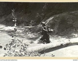 FARIA RIVER, NEW GUINEA. 1944-01-20. A MEMBER OF THE 2/9TH INFANTRY BATTALION WADING THROUGH THE FAST FLOWING FARIA RIVER ON HIS WAY TO THE FRONT LINE