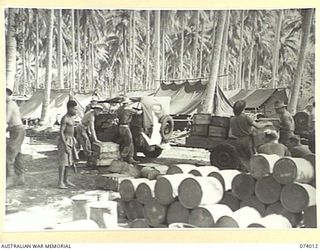 MILILAT, NEW GUINEA. 1944-06-19. NEW GUINEA NATIVES AND AUSTRALIAN ARMY SERVICE CORPS PERSONNEL OF HEADQUARTERS, 5TH DIVISION LOADING SUPPLIES ON TO JEEP TRAILERS FOR TRANSPORT TO UNITS IN THE AREA
