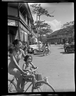 Street scene showing woman and child on a bicycle, Papeete, Tahiti