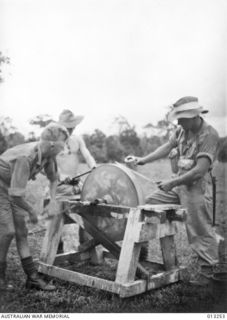 NEW GUINEA. C. 1942-09-01. THE SPIRIT OF DETERMINATION IS PORTRAYED IN THIS PHOTOGRAPH TAKEN BEHIND THE LINES IN NEW GUINEA. IT SHOWS MEN OF AN AUSTRALIAN INFANTRY UNIT SHARPENING THEIR BAYONETS ..