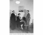 Lauren Donaldson and Arthur Welander with Lois Thayer at a Christmas party displaying her painting of the bomb, December 23, 1947