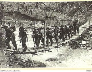 FARIA VALLEY, NEW GUINEA. 1944-02-10. PERSONNEL OF THE 11TH FIELD BATTERY, 4TH FIELD REGIMENT, ON A ROPE SUSPENSION BRIDGE CROSSING THE FARIA RIVER NEAR GUY'S POST IN THEIR MOVE TO FORWARD ..