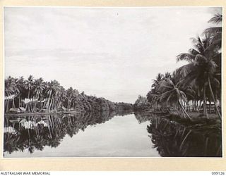 BUNA-GONA AREA, NEW GUINEA. 1945-10-15. GONA, THREE YEARS AFTER THE TIDE OF WAR HAD PASSED THE AREA, NOW A PEACEFUL VILLAGE SITUATED ON BOTH SIDES OF A CANAL LIKE RIVER