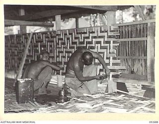 TOROKINA, BOUGAINVILLE. 1945-05-31. SAPPER R. BANKS (1) AND SAPPER E.T. PARNHAM (2), MEMBERS OF 10 FIELD COMPANY ROYAL AUSTRALIAN ENGINEERS, NAILING BAMBOO PATTERN SCREENS ON THE WALLS OF ..