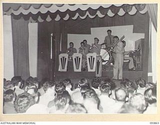 LAE AREA, NEW GUINEA, 1945-07-09. THE REGIMENTAL HEADQUARTERS 2/1 GUARD REGIMENT DANCE BAND PERFORMING DURING THE 19 LINES OF COMMUNICATION AREA SIGNALS REVUE "OVER TO YOU". IT WAS HELD AT THE ..