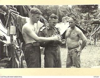 KOROPA, NEW GUINEA. 1944-02-03. VX111856 SERGEANT I.W. ROPER (1) AND VX139984 CORPORAL A.M. JENKINS (3) OF THE 15TH INFANTRY BRIGADE PICTURED WITH MR. W.A. ALVIN (2) THE RED SHIELD REPRESENTATIVE ..