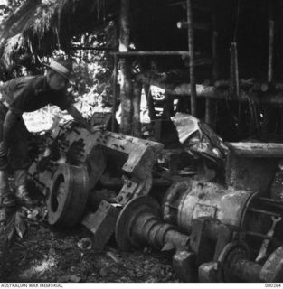 AWAR, NEW GUINEA. 1944-07-10. NX112718 CAPTAIN S.D. NICHOLSON, 8TH BRIGADE, LIGHT AID DETACHMENT, EXAMINES A JAPANESE MARINE ENGINE IN AN AREA UNDER SALVAGE BY THE 5TH DIVISION SALVAGE GROUP