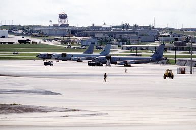 A left side view of KC-135 Stratotanker aircraft parked in line on a ramp with base facilities in the background. The aircraft are assigned to the 43rd Strategic Wing, Pacific Task Force