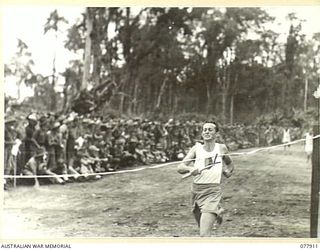 TOROKINA, BOUGAINVILLE ISLAND. 1945-01-01. PRIVATE A. DOMBRIAN WINNING THE MILE RELAY RACE AT THE ATHLETIC MEETING ORGANISED BY HEADQUARTERS, 3RD DIVISION