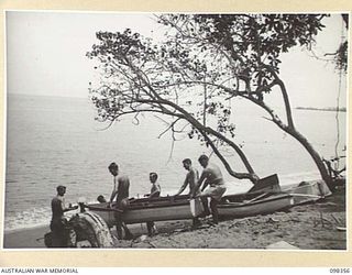 WEWAK, NEW GUINEA. 1945-10-28. THE CREW OF THE MISTAKE, MEMBERS OF 16 INFANTRY BRIGADE, CARRYING THE BOAT TO THE BEACH PRIOR TO ITS LAUNCHING. THE MISTAKE IS AN ENTRY IN THE WEWAK REGATTA TO BE ..