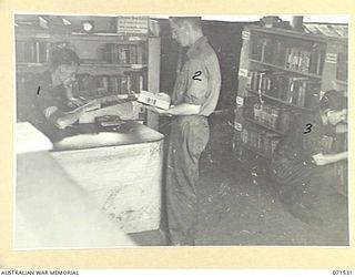 KOITAKI, PORT MORESBY AREA, NEW GUINEA, 1944-03-27. VX118216 CORPORAL W. A. WARREN, LIBRARIAN, AUSTRALIAN ARMY EDUCATION SERVICE ATTACHED TO THE 113TH CONVALESCENT DEPOT, EXAMINING THE RECORDS FOR ..