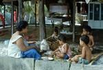 Mother feeding children in open fale (house).