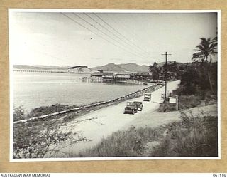 HANUABADA, NEW GUINEA. 1943-12-01. THE HANUABADA NATIVE VILLAGE IN THE MIDDLE DISTANCE WITH THE PORT MORESBY OIL PIPELINE WHARF IN THE LEFT BACKGROUND