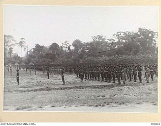 TOROKINA, BOUGAINVILLE, 1945-07-11. TROOPS OF 11 INFANTRY BRIGADE PRESENT ARMS FOR THE GENERAL SALUTE PRIOR TO INSPECTION BY LIEUTENANT-GENERAL S.G. SAVIGE, GENERAL OFFICER COMMANDING 2 CORPS, AT ..